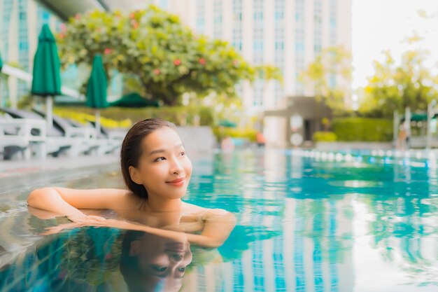 Portrait belle jeune femme asiatique se détendre sourire heureux loisirs autour de la piscine extérieure