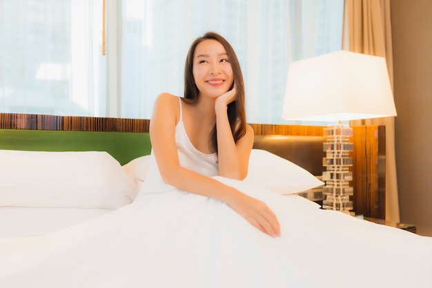 Portrait belle jeune femme asiatique se détendre sourire sur le lit à l'intérieur de la chambre