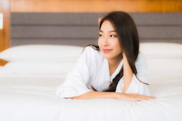 Portrait belle jeune femme asiatique se détendre sourire sur le lit à l'intérieur de la chambre