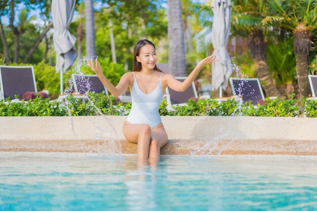 Portrait belle jeune femme asiatique se détendre sourire loisirs autour de la piscine extérieure avec mer océan en vacances de voyage