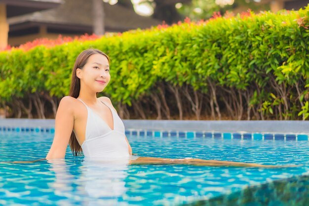 Portrait belle jeune femme asiatique se détendre sourire loisirs autour de la piscine extérieure près de la mer