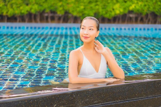 Portrait belle jeune femme asiatique se détendre sourire loisirs autour de la piscine extérieure près de la mer