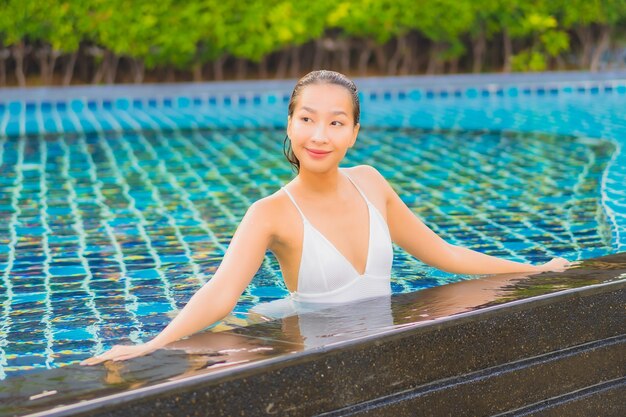 Portrait belle jeune femme asiatique se détendre sourire loisirs autour de la piscine extérieure près de la mer