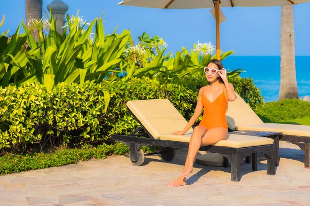 Portrait belle jeune femme asiatique se détendre sourire loisirs autour de la piscine extérieure avec vue sur l'océan mer