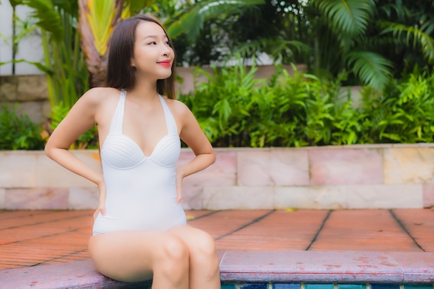 Portrait belle jeune femme asiatique se détendre sourire loisirs autour de la piscine extérieure