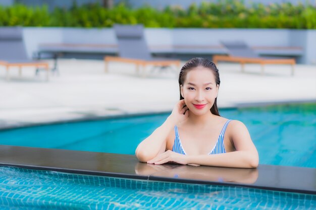 Portrait belle jeune femme asiatique se détendre sourire loisirs autour de la piscine extérieure