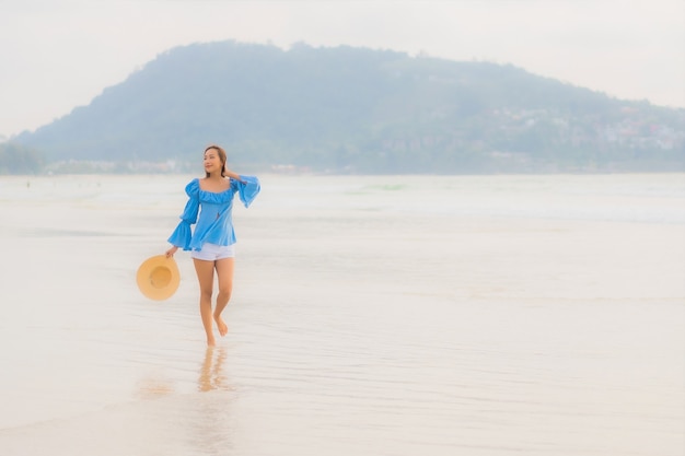 Portrait belle jeune femme asiatique se détendre sourire de loisirs autour de la plage mer océan au moment du coucher du soleil