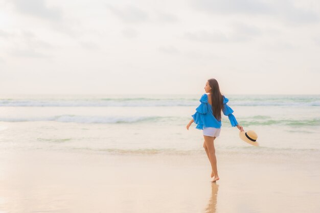 Portrait belle jeune femme asiatique se détendre sourire de loisirs autour de la plage mer océan au moment du coucher du soleil