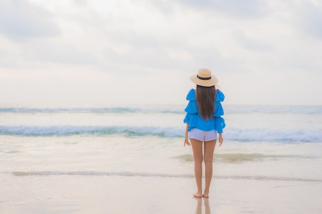 Portrait belle jeune femme asiatique se détendre sourire de loisirs autour de la plage mer océan au moment du coucher du soleil