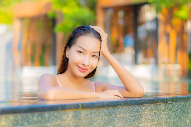Portrait belle jeune femme asiatique se détendre sourire profiter de loisirs autour de la piscine dans l'hôtel resort