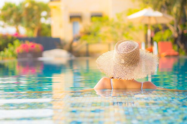 Portrait belle jeune femme asiatique se détendre sourire profiter de loisirs autour de la piscine dans l'hôtel de villégiature en vacances
