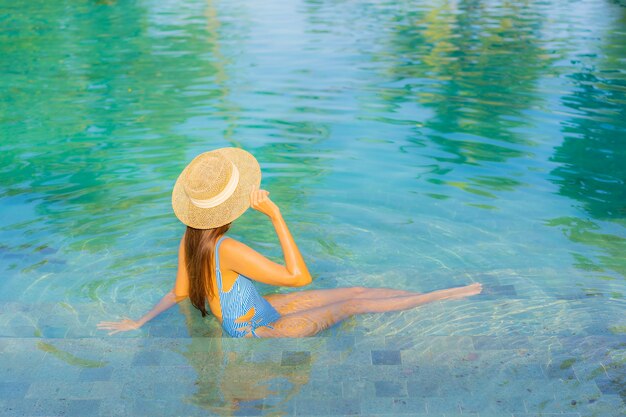 Portrait belle jeune femme asiatique se détendre sourire profiter de loisirs autour de la piscine près de la mer plage vue sur l'océan en vacances