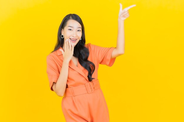 Portrait belle jeune femme asiatique sourire avec action sur jaune