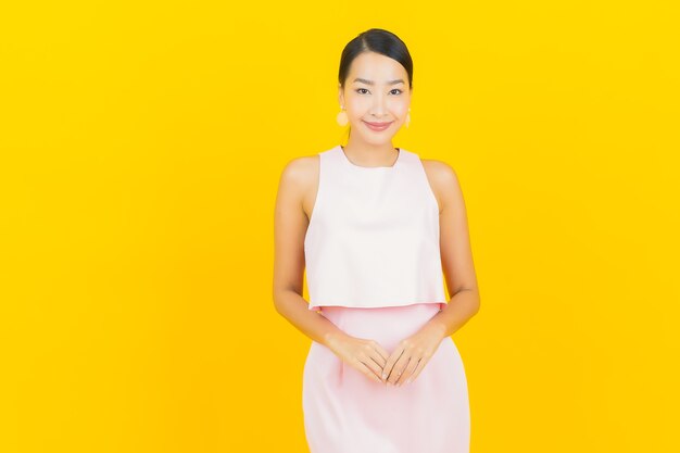 Portrait belle jeune femme asiatique sourire avec action sur jaune