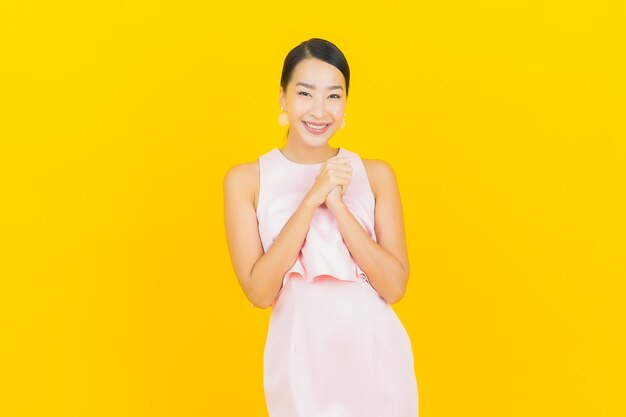 Portrait belle jeune femme asiatique sourire avec action sur jaune