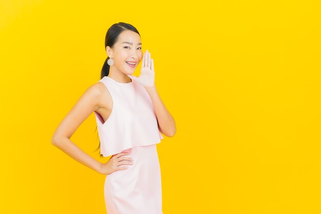 Portrait belle jeune femme asiatique sourire avec action sur jaune