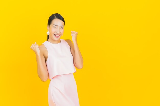 Portrait belle jeune femme asiatique sourire avec action sur jaune