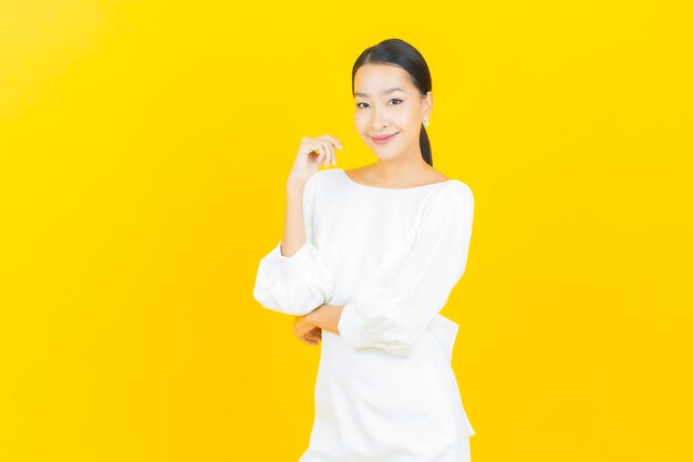 Portrait belle jeune femme asiatique sourire avec action sur jaune