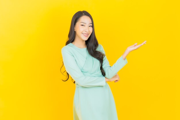 Portrait belle jeune femme asiatique sourire avec action sur jaune