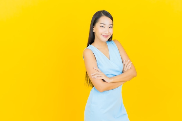 Portrait belle jeune femme asiatique sourire avec action sur le mur de couleur jaune