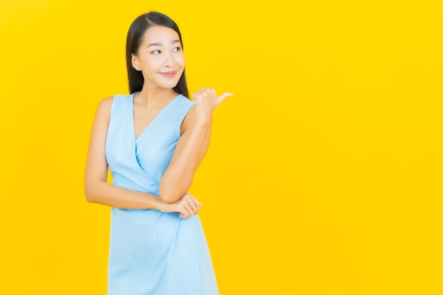 Portrait belle jeune femme asiatique sourire avec action sur le mur de couleur jaune