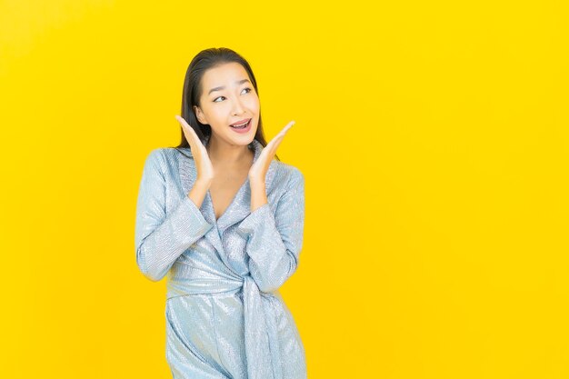 Portrait belle jeune femme asiatique sourire avec action sur mur jaune