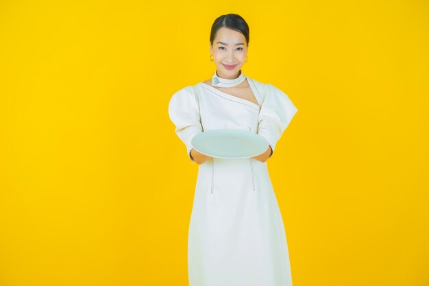 Portrait belle jeune femme asiatique sourire avec assiette vide sur fond de couleur