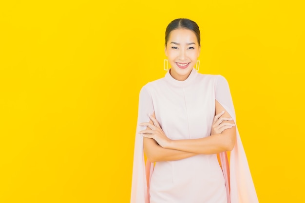 Portrait belle jeune femme asiatique sourire avec beaucoup d'action sur le mur jaune