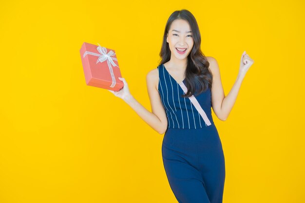 Portrait belle jeune femme asiatique sourire avec boîte-cadeau rouge sur