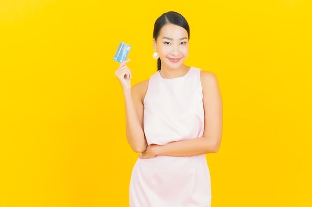 Portrait belle jeune femme asiatique sourire avec carte de crédit sur jaune