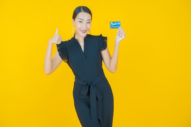 Portrait belle jeune femme asiatique sourire avec carte de crédit sur jaune