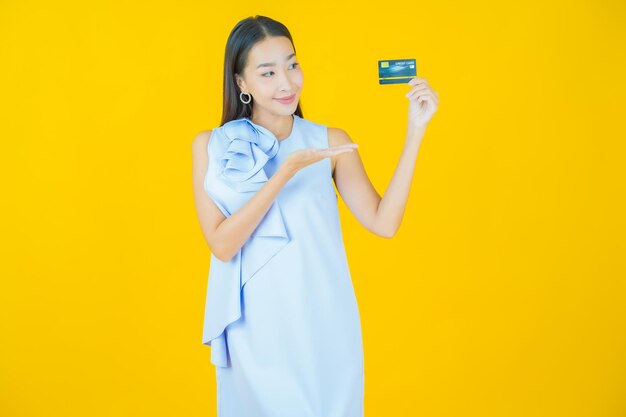 Portrait belle jeune femme asiatique sourire avec carte de crédit sur jaune