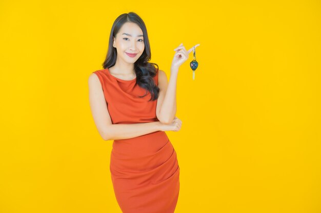 Portrait belle jeune femme asiatique sourire avec clé de voiture sur jaune