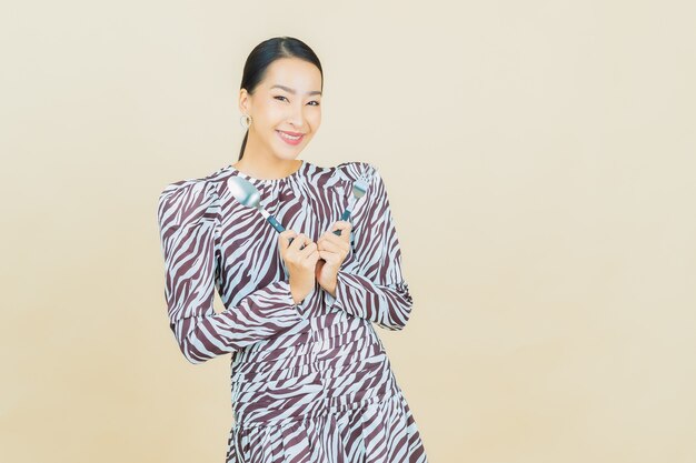 Portrait belle jeune femme asiatique sourire avec cuillère et fourchette sur beige