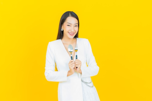 Portrait belle jeune femme asiatique sourire avec cuillère et fourchette