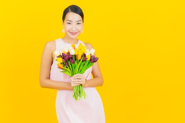 Portrait belle jeune femme asiatique sourire avec fleur sur jaune