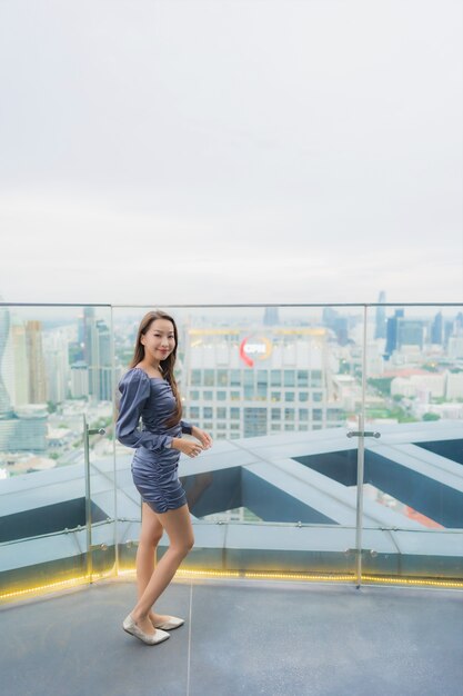 Portrait belle jeune femme asiatique sourire heureux sur le restaurant sur le toit autour de vue sur la ville