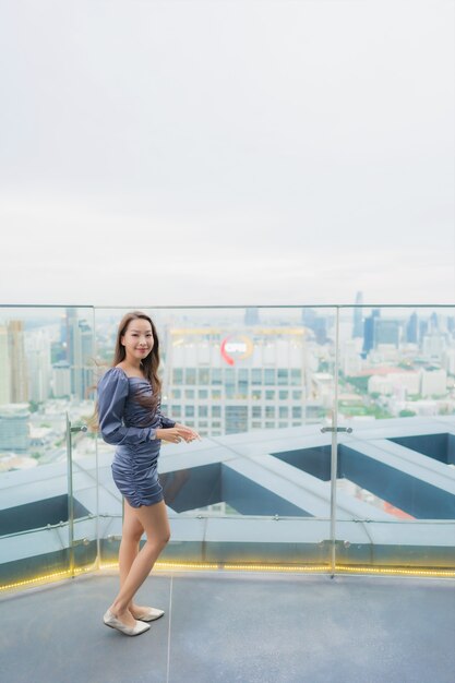 Portrait belle jeune femme asiatique sourire heureux sur le restaurant sur le toit autour de vue sur la ville