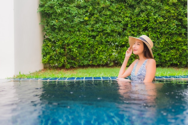 Portrait belle jeune femme asiatique sourire heureux se détendre autour de la piscine extérieure de l'hôtel resort