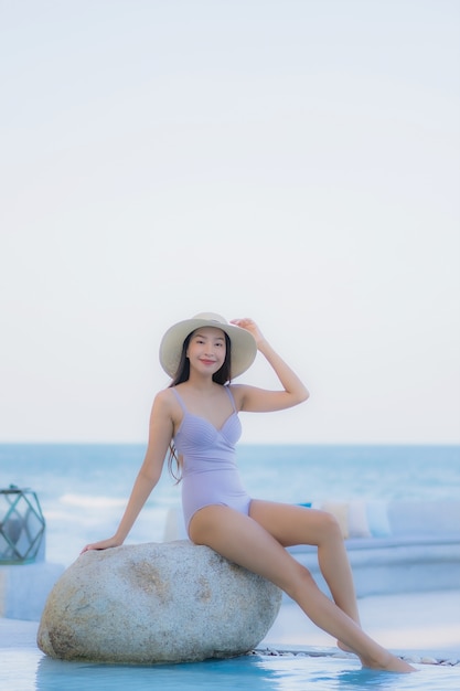 Portrait belle jeune femme asiatique sourire heureux se détendre autour de la piscine extérieure de l'hôtel resort