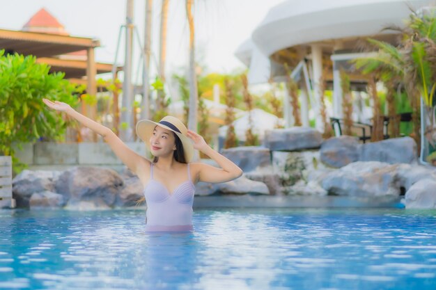 Portrait belle jeune femme asiatique sourire heureux se détendre autour de la piscine extérieure de l'hôtel resort