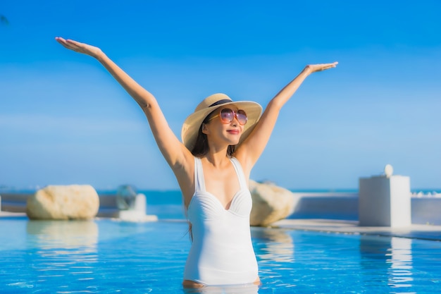 Portrait belle jeune femme asiatique sourire heureux se détendre autour de la piscine extérieure de l'hôtel resort