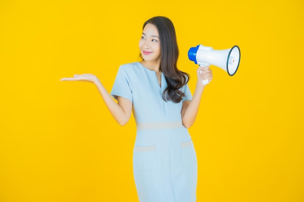 Photo gratuite portrait belle jeune femme asiatique sourire avec mégaphone sur fond de couleur