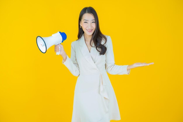 Portrait belle jeune femme asiatique sourire avec mégaphone sur fond de couleur