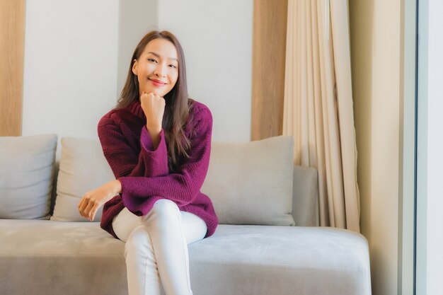 Portrait belle jeune femme asiatique sourire se détendre sur le canapé à l'intérieur du salon