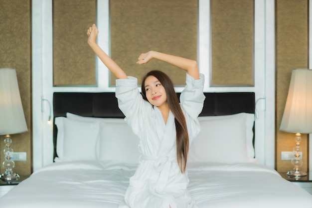 Portrait belle jeune femme asiatique sourire se détendre sur le lit à l'intérieur de la chambre