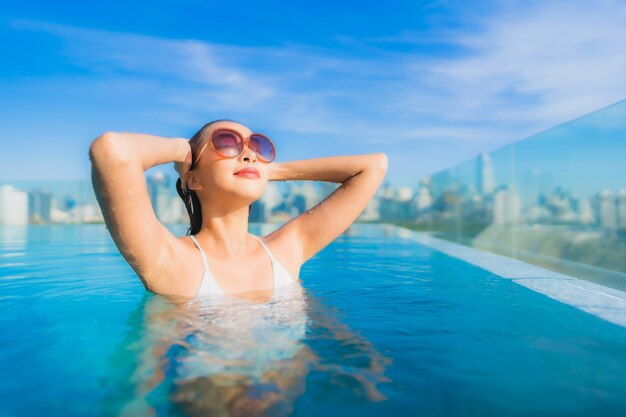 Portrait belle jeune femme asiatique sourire se détendre loisirs autour de la piscine extérieure avec vue sur la ville