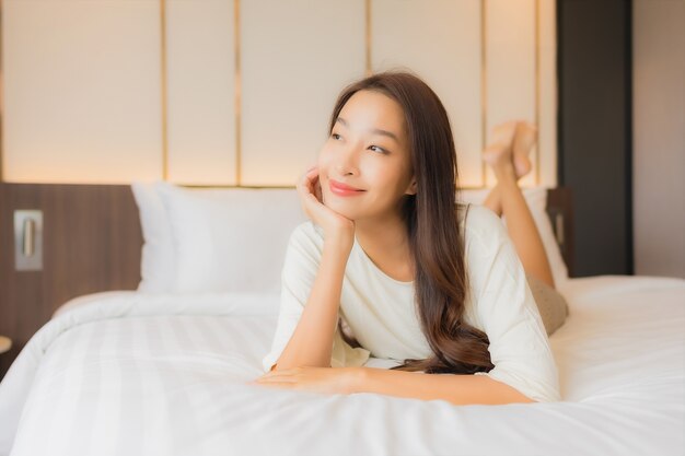 Portrait belle jeune femme asiatique sourire se détendre loisirs sur le lit à l'intérieur de la chambre