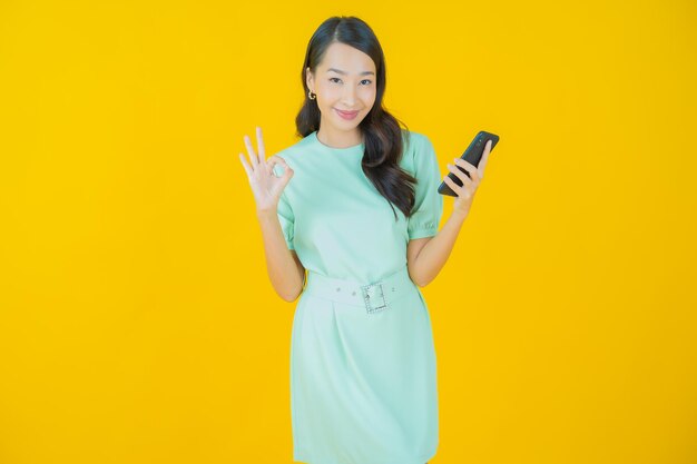 Portrait belle jeune femme asiatique sourire avec téléphone mobile intelligent sur fond de couleur