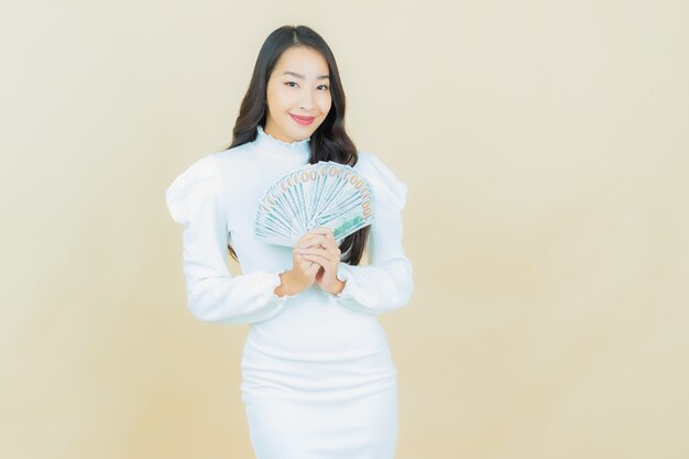 Portrait de belle jeune femme asiatique sourit avec beaucoup d'argent et d'argent sur le mur de couleur